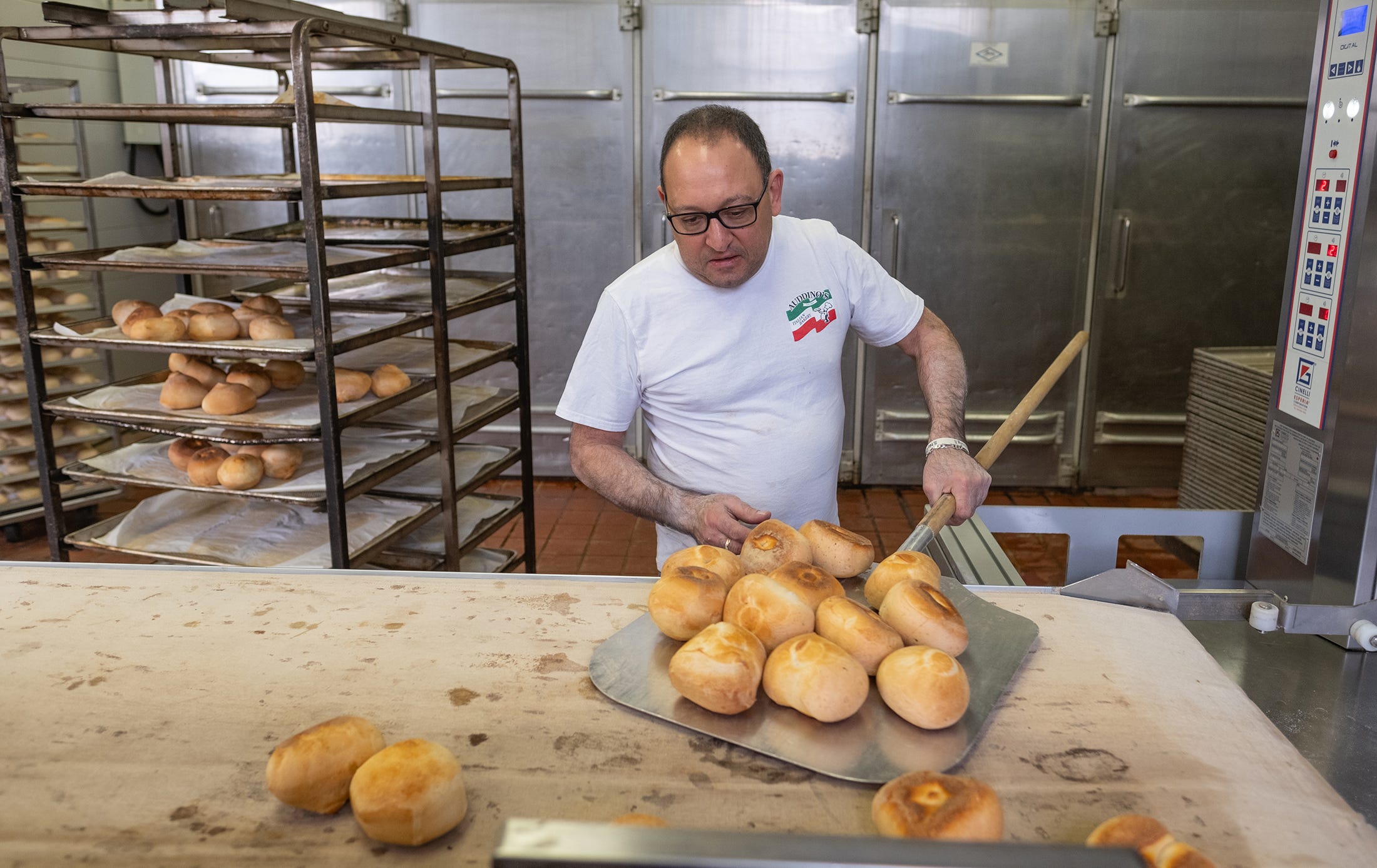 Marco Auddino pulls freshly baked buns from one of the ovens at Auddino’s Italian Bakery.