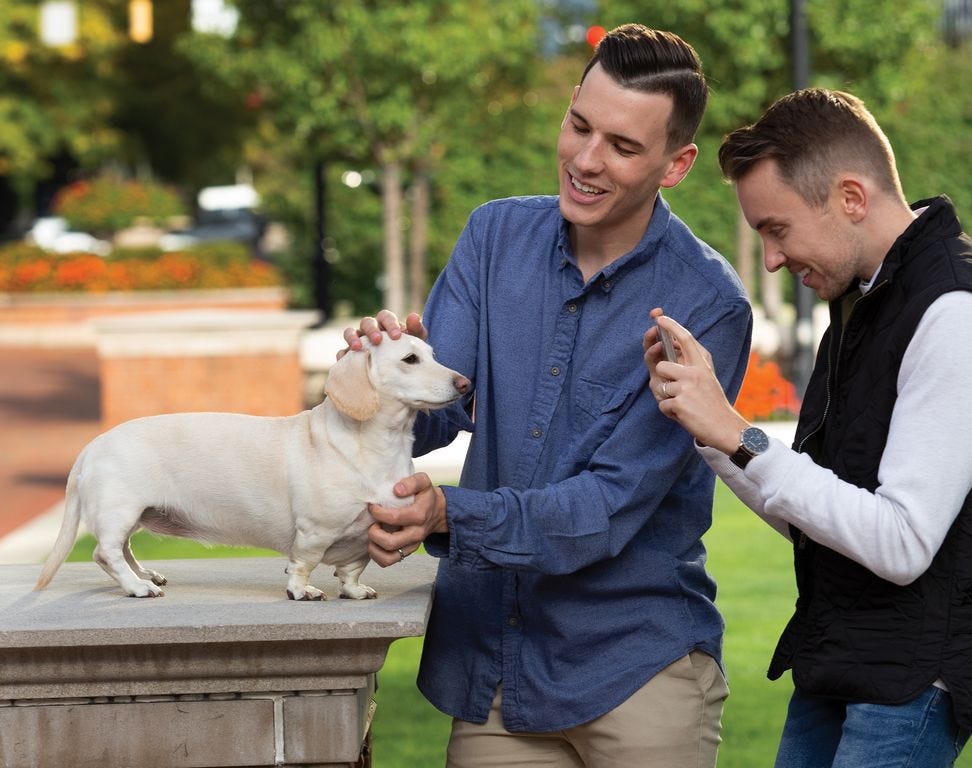Ben Campbell and Logan Hickman pose their dog, Whitney Chewston, for a photo at the Columbus Commons park Downtown.